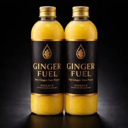 Twee flessen Gingerfuel essence naast elkaar op een donkere achtergrond, met goud-zwarte labels en condensdruppels op de flessen.